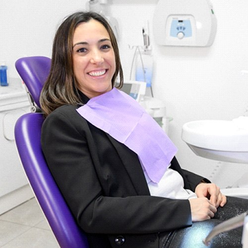 Smiling female patient sitting in dental chair