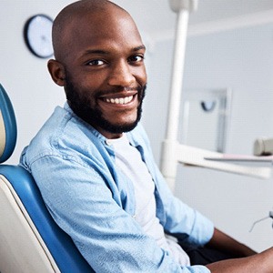 Man leaning forward in dental chair and smiling