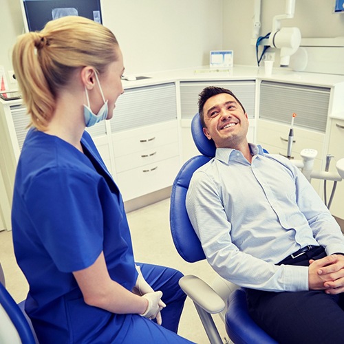 man sitting in dental chair and smiling at dentist 