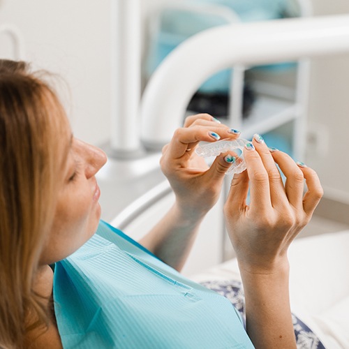 Smiling patient holding clear aligner