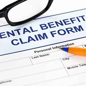 Top portion of dental benefits claim form with pen and glasses