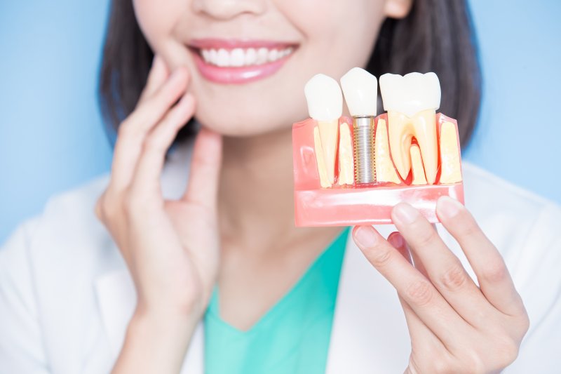 A closeup of a dentist holding a dental implant model